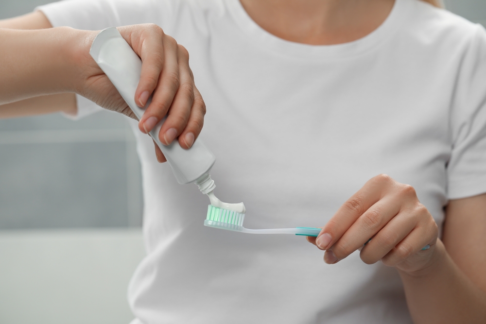 femeie care foloseste pasta de dinti cu fluor