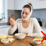 Woman with a dental bandage eating soft soup and fruit while a red X marks out forbidden hard foods like a burger and fries.