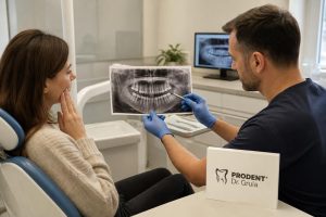 Dentist in blue gloves showing a panoramic dental X-ray to a female patient holding her jaw in a bright, modern clinic.